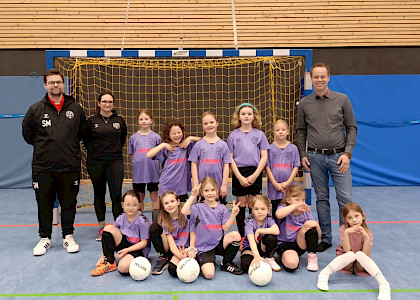 Die F-Mädchen sitzen zusammen und der Sponsor und der Trainer stehen links und rechts neben ihnen. sie freuen sich über die neuen Trikots Die F-Mädchen sitzen zusammen und der Sponsor und der Trainer stehen links und rechts neben ihnen. sie freuen sich über die neuen Trikots